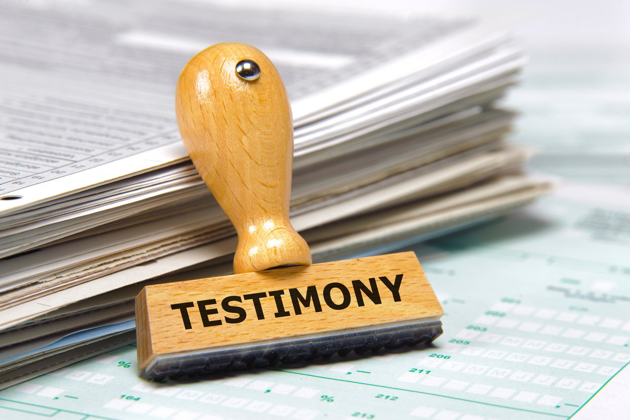 testimony printed on rubber stamp laying on stack of documents